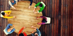 Diverse group of children sitting around a large wooden table, viewed from above.