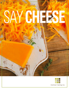Block and shreds of sharp cheddar cheese on a white board with the text Say Cheese