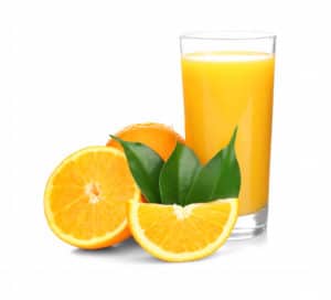 Fresh glass of orange juice next to cut oranges