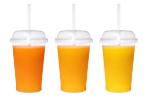 Three clear plastic cups containing different variations of orange juice for sensory testing