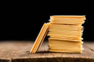 Stack of individually plastic-wrapped orange cheese slices on a rustic wooden table.